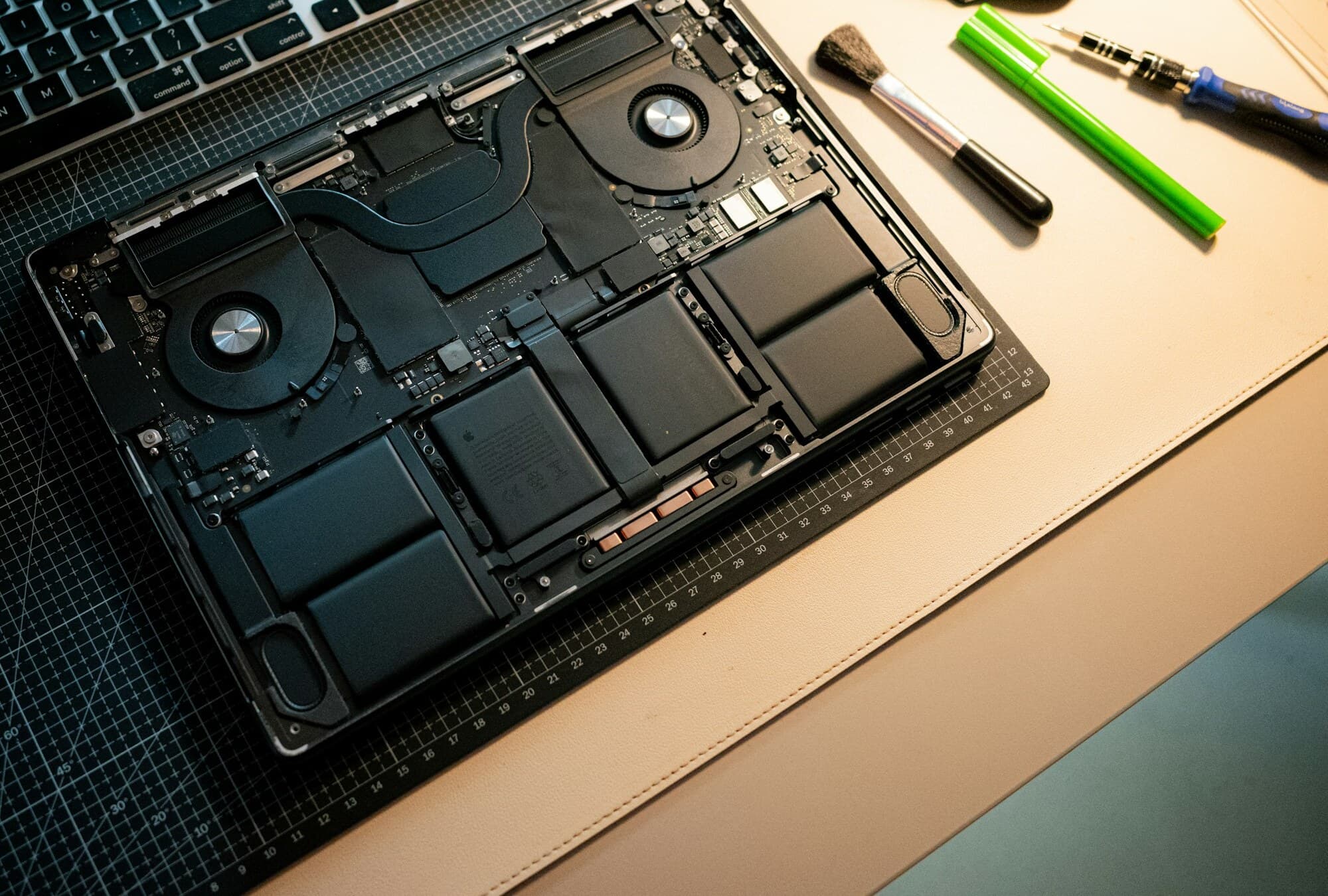 A laptop opened for repair with its internals and tools visible